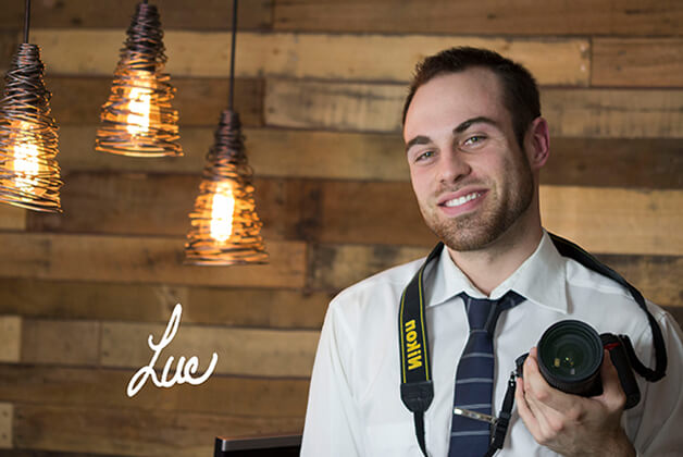 Headshot of Luc Chrétien holding digital camera with his signature